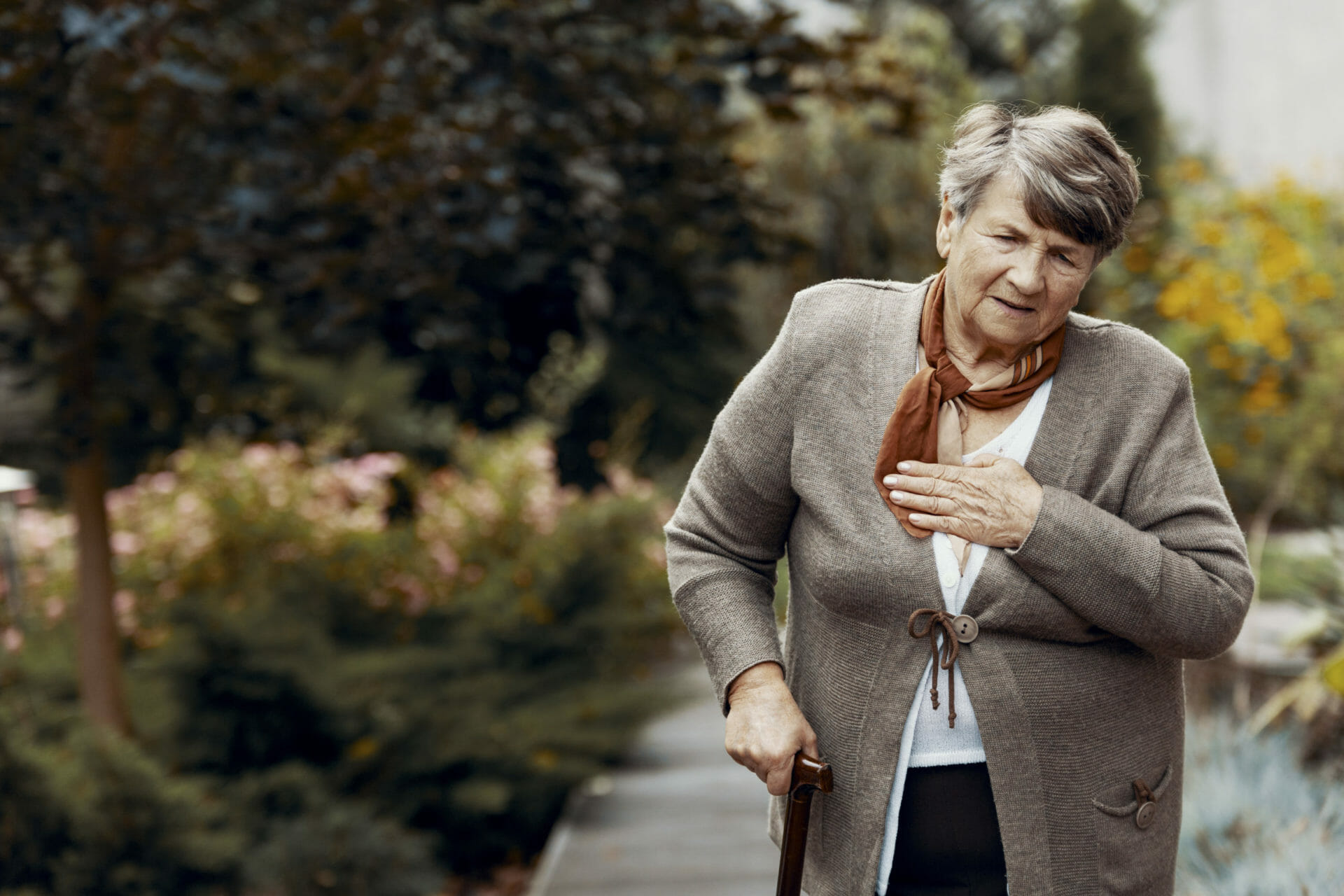 Weak senior woman with walking stick waiting for help during breathlessness attack Weak senior woman with walking stick waiting for help during breathlessness attack